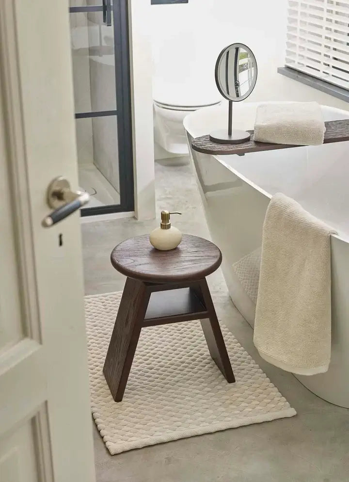 Schminkspiegel Ario von Aquanova im Badezimmer kombiniert mit Holzhocker Cosmo und Maks Badteppich – moderne Badeinrichtung in warmen Naturtönen