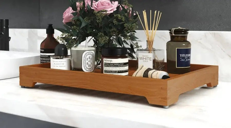 Dekoratives Holztablett mit Blumen, Duftkerzen und Badaccessoires auf einer hellen Ablage
