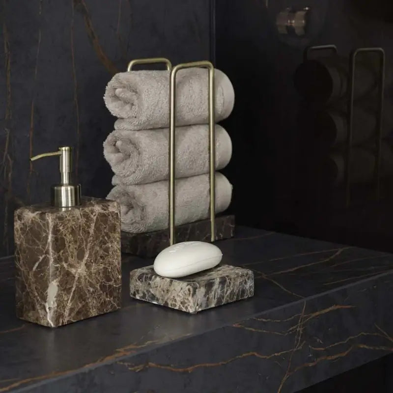 Dunkles Marmor-Badezimmer mit aufgerollten Handtüchern in Taupe und Marmor-Accessoires in Braun – Spa-Look mit anthrazitfarbenen Fliesen
