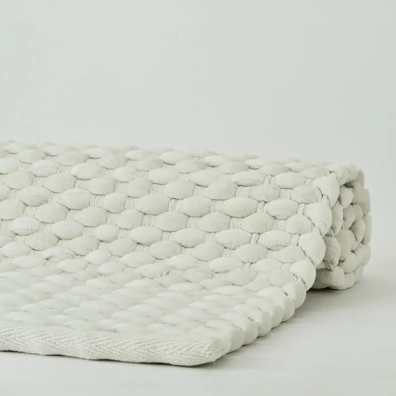 Badteppich Maks von Aquanova in Pearl Cremeweiß, Detailaufnahme der noppenartigen Struktur und eingefassten Kante
