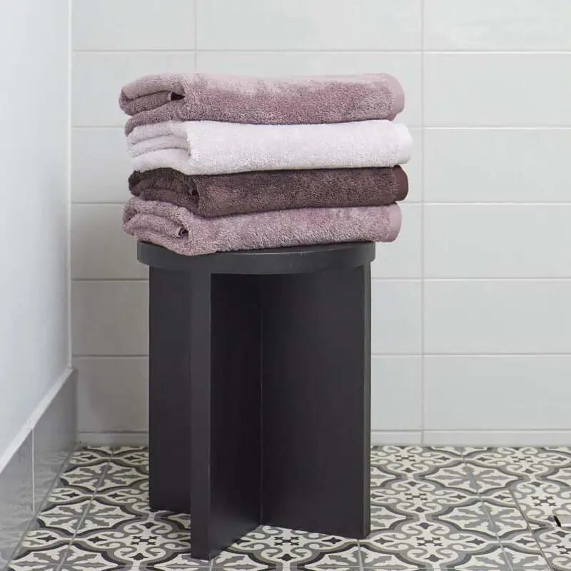 Moderner Badhocker im Badezimmer als stilvolle Ablagefläche für Handtücher und Deko