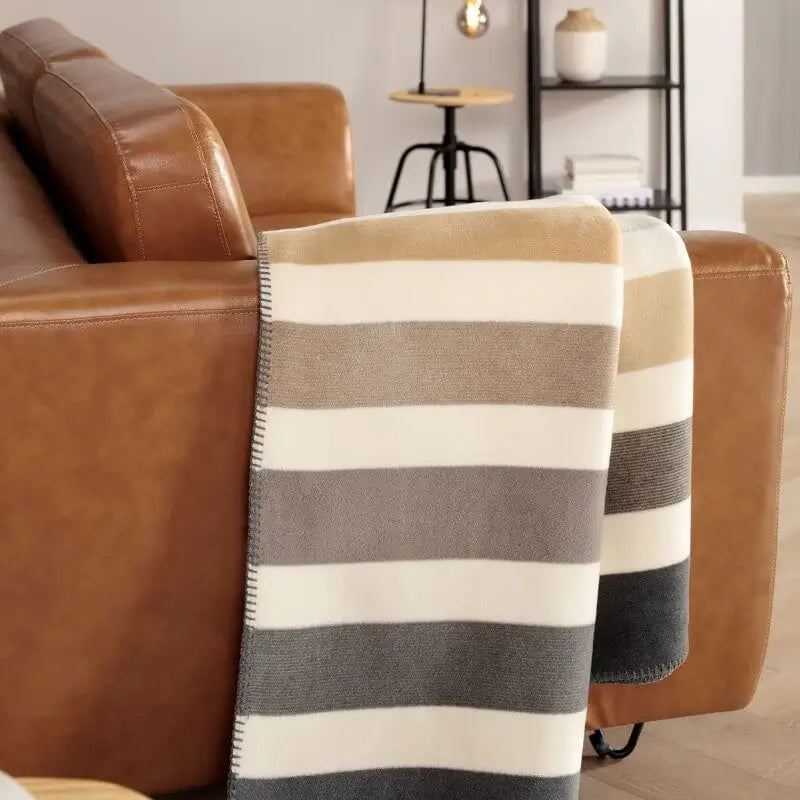 Schöne Sofadecke in modernem Wohnzimmer als Dekoration und Kuscheldecke auf dem Sofa