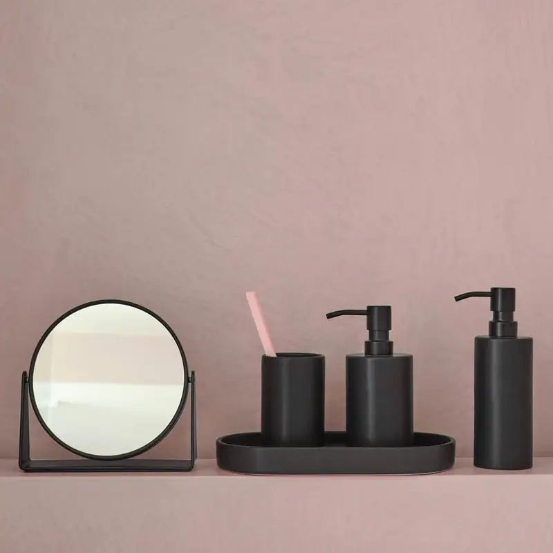 Modernes Badezimmer mit schwarzen Badaccessoires wie Seifenspender, WC-Bürste und Ablage – stilvoll kombiniert mit hellen Fliesen und neutralen Textilien