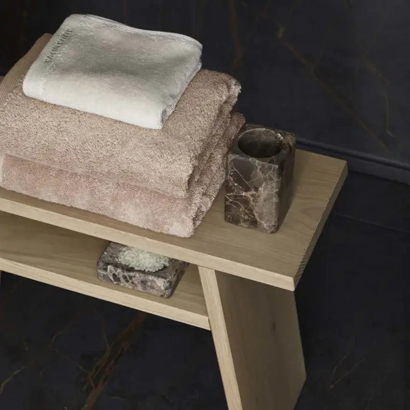 Stilvolles Spa-Badezimmer mit Holzhocker und Marmor-Accessoires für eine moderne Wellness-Atmosphäre im Bad.