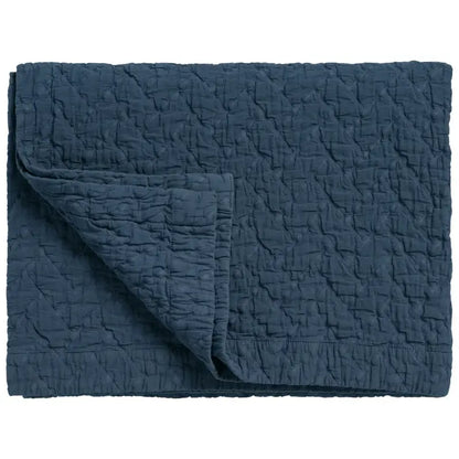 Tagesdecke Pure 10 in Blue Ink Dunkelblau, gefalteter Bettüberwurf mit strukturierter Oberfläche und umgeschlagener Ecke
