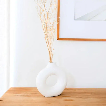 Weiße Tonvase Nusa in moderner Ringform auf Holztisch im hellen Wohnambiente.